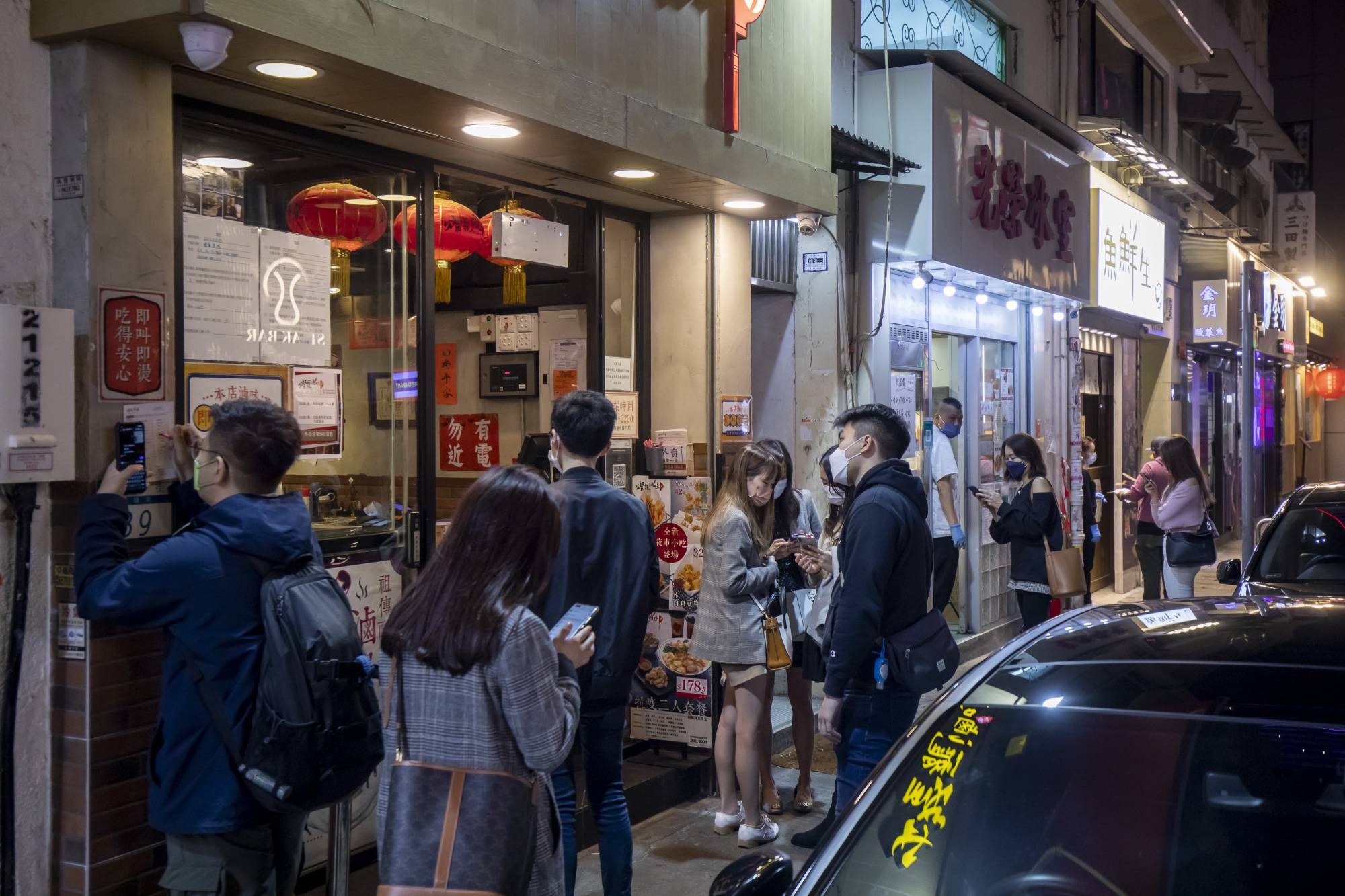 Customers wait for take-out food outside restaurants in the Causeway Bay of Hong Kong on Friday. | Bloomberg 