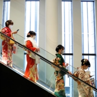 Women wearing kimonos ride on an escalator at a Coming of Age Day celebration ceremony venue in Tokyo on Monday. | REUTERS