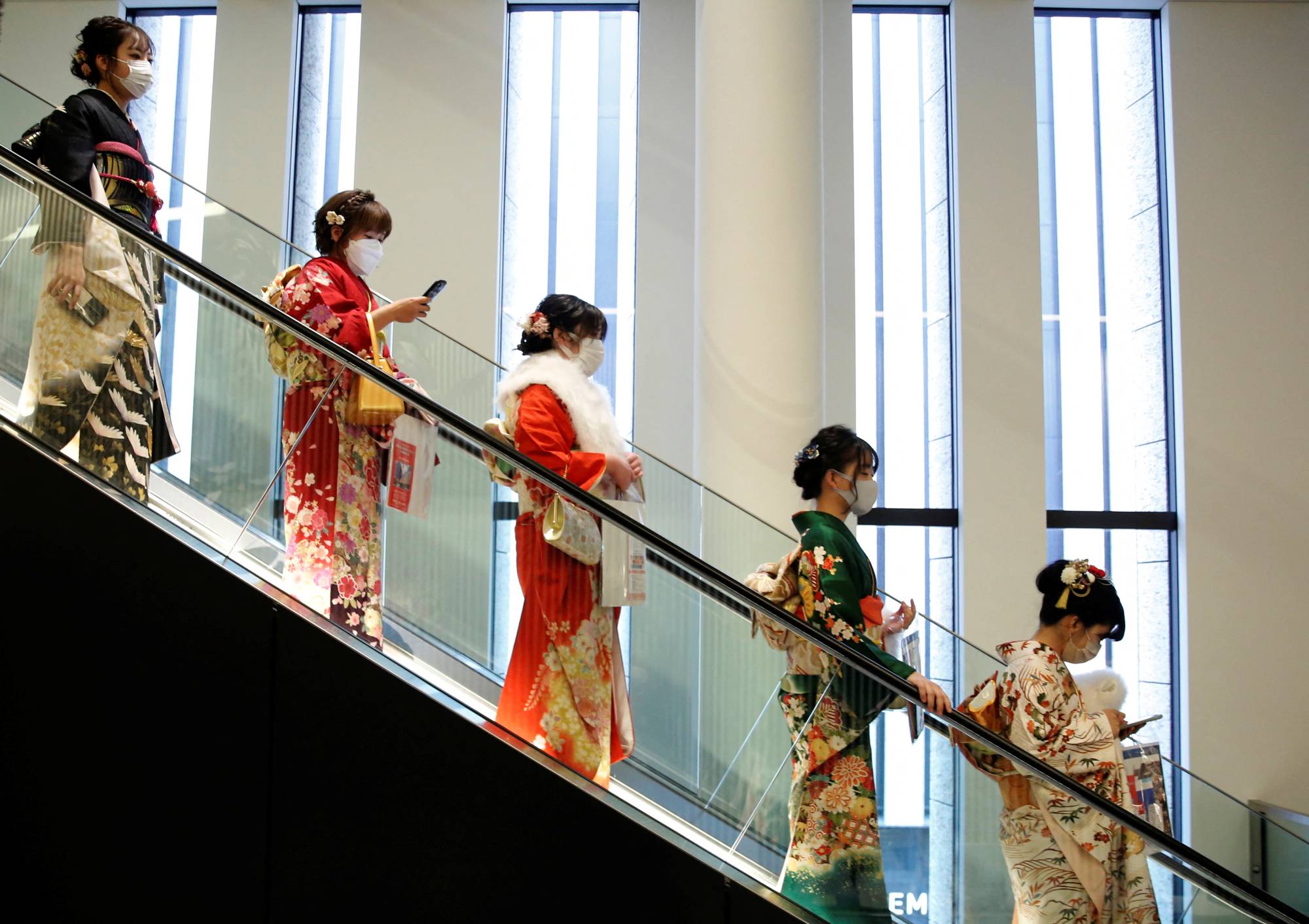 Women wearing kimonos ride on an escalator at a Coming of Age Day celebration ceremony venue in Tokyo on Monday. | REUTERS