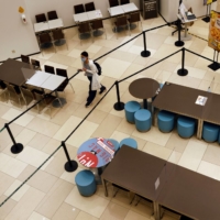 A woman walks past empty seats and tables at a McDonald\'s after dine-in services were suspended, following tighter restrictions to curb the spread of COVID-19 in Hong Kong on Jan. 9. | REUTERS