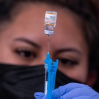 A health care worker prepares a dose of the Pfizer-BioNTech COVID-19 vaccine in San Francisco on Jan. 10. | BLOOMBERG