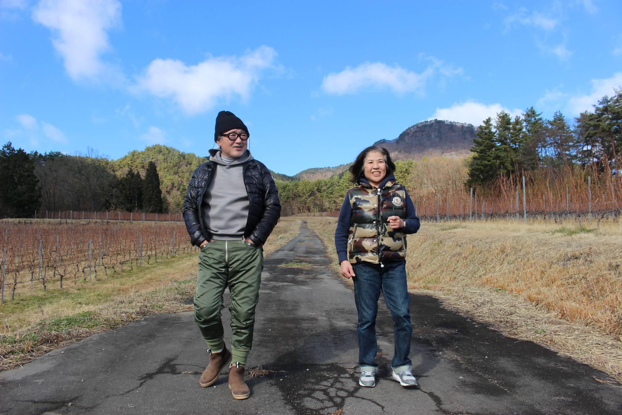 Toyohiko and Michiko Kanehashi stroll through their vineyard, with the sacred mountain Komayumidake visible in the background. | JOJI SAKURAI