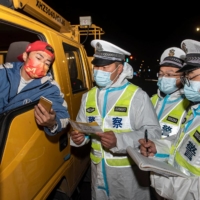 Police officers check information with a truck driver at a check point in Ningbo, in China\'s eastern Zhejiang province, on Dec. 18. | AFP-JIJI
