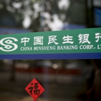 The Chinese word for prosperity is stuck below signage for China Minsheng Banking Corp. at a branch in Guangzhou in March 2014. | BLOOMBERG