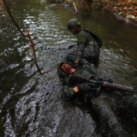 An ARP trainee pulls a fellow trainee, who is pretending to be injured, through sewage contaminated water during the last week of a ten week program to become members of the Taiwan navy\'s elite Amphibious Reconnaissance and Patrol unit, at Zuoying navy base in Kaohsiung on Dec. 21.  | REUTERS