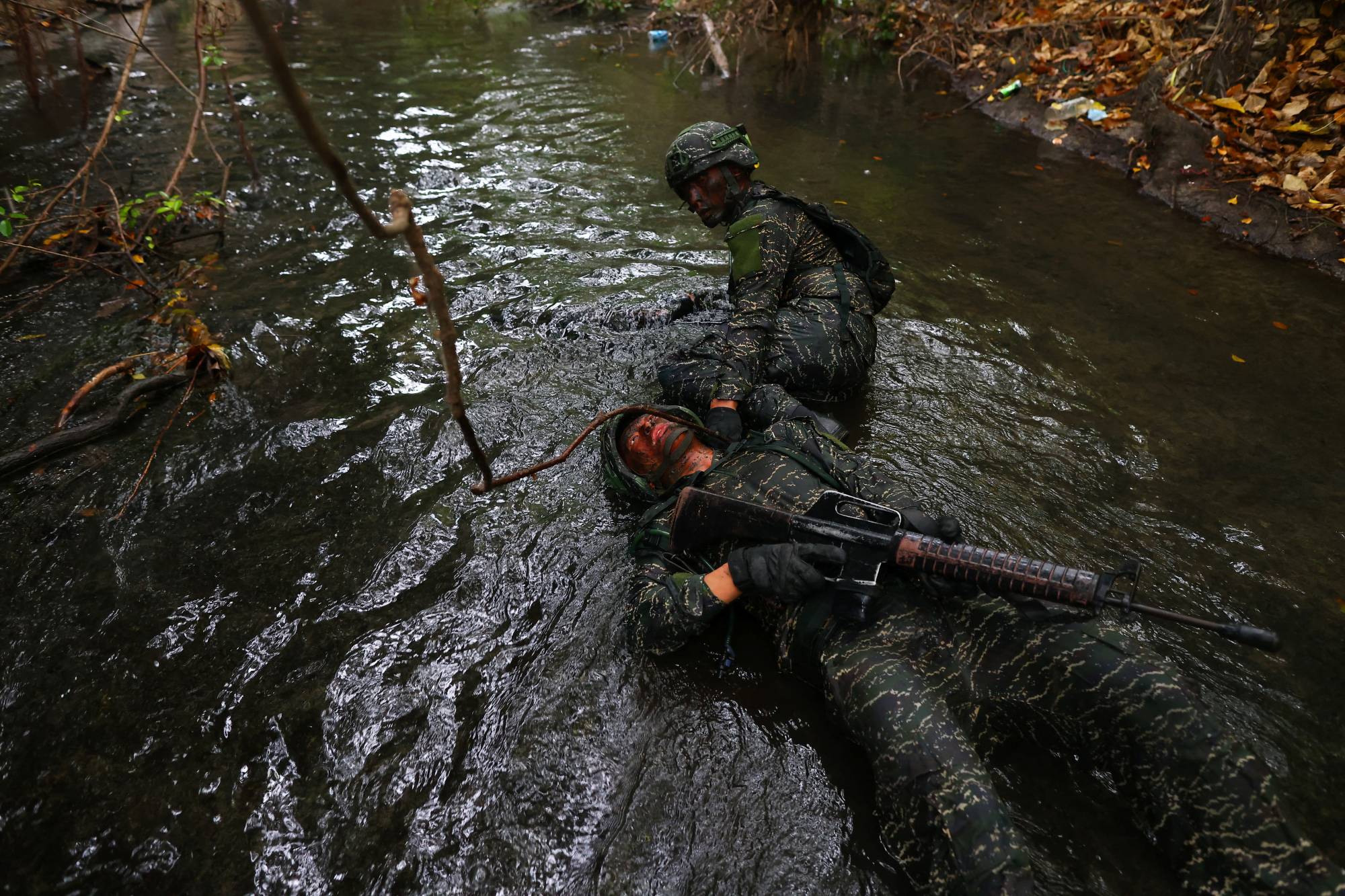 An ARP trainee pulls a fellow trainee, who is pretending to be injured, through sewage contaminated water during the last week of a ten week program to become members of the Taiwan navy's elite Amphibious Reconnaissance and Patrol unit, at Zuoying navy base in Kaohsiung on Dec. 21.  | REUTERS
