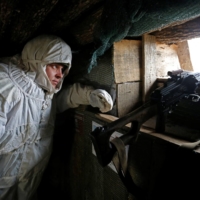 A militant with the self-proclaimed Donetsk People\'s Republic observes the area at fighting positions on the line of separation with the Ukrainian armed forces near the rebel-controlled settlement of Yasne in Ukraine on Friday. | REUTERS