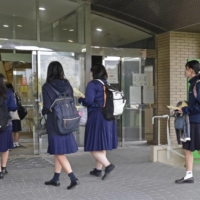 Students head into university entrance exams at the University of the Ryukyus in Nishihara, Okinawa Prefecture, on Saturday.  | KYODO 