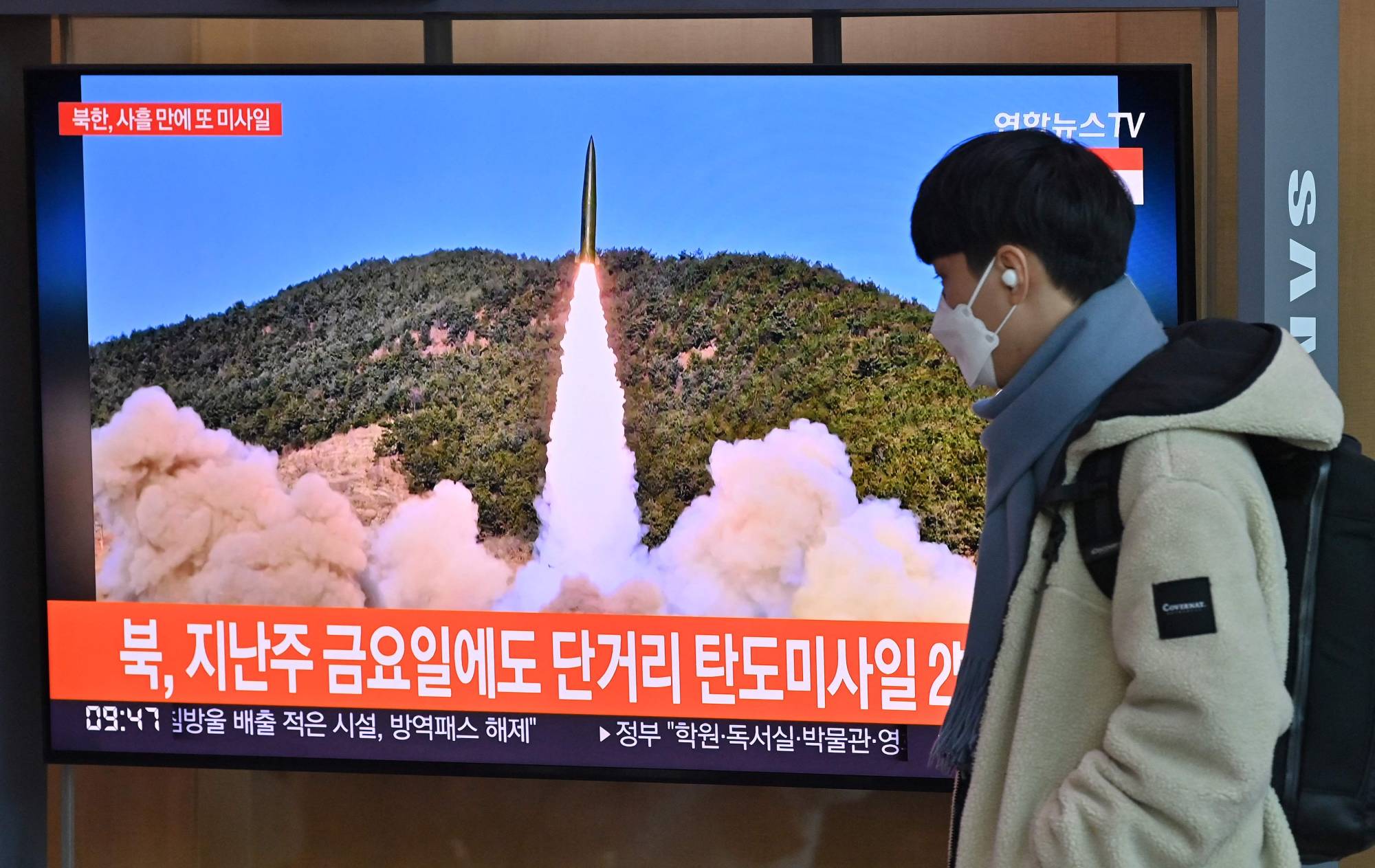 A man walks past a TV screen showing file footage of a North Korean missile test, at the main railway station in Seoul on Monday. | AFP-JIJI