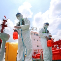 Police officers spray disinfectant at Nanjing port in China\'s eastern Jiangsu province in August. | AFP-JIJI