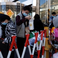 People pick up delivered food in an enclosure outside an office building in Beijing on Jan. 13. | REUTERS 