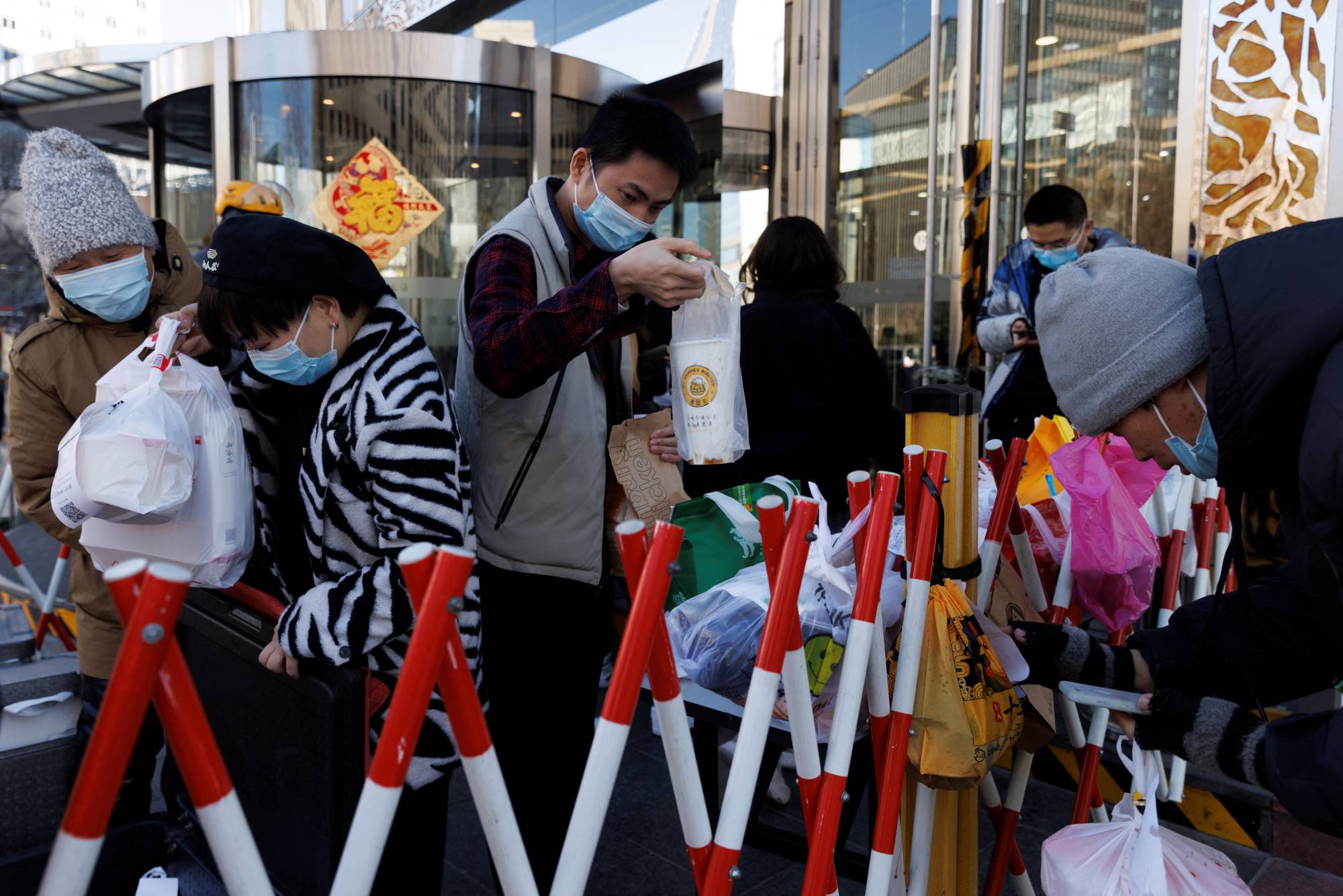 People pick up delivered food in an enclosure outside an office building in Beijing on Jan. 13. | Reuters 