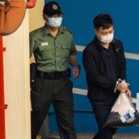 Ryan Law, editor-in-chief of the now-defunct Apple Daily newspaper, is escorted to a Correctional Services Department vehicle at the Lai Chi Kok Reception Center to be transported to the West Kowloon Magistrates\' Courts for a hearing in Hong Kong, China, on Friday, Aug. 13, 2021. | BLOOMBERG