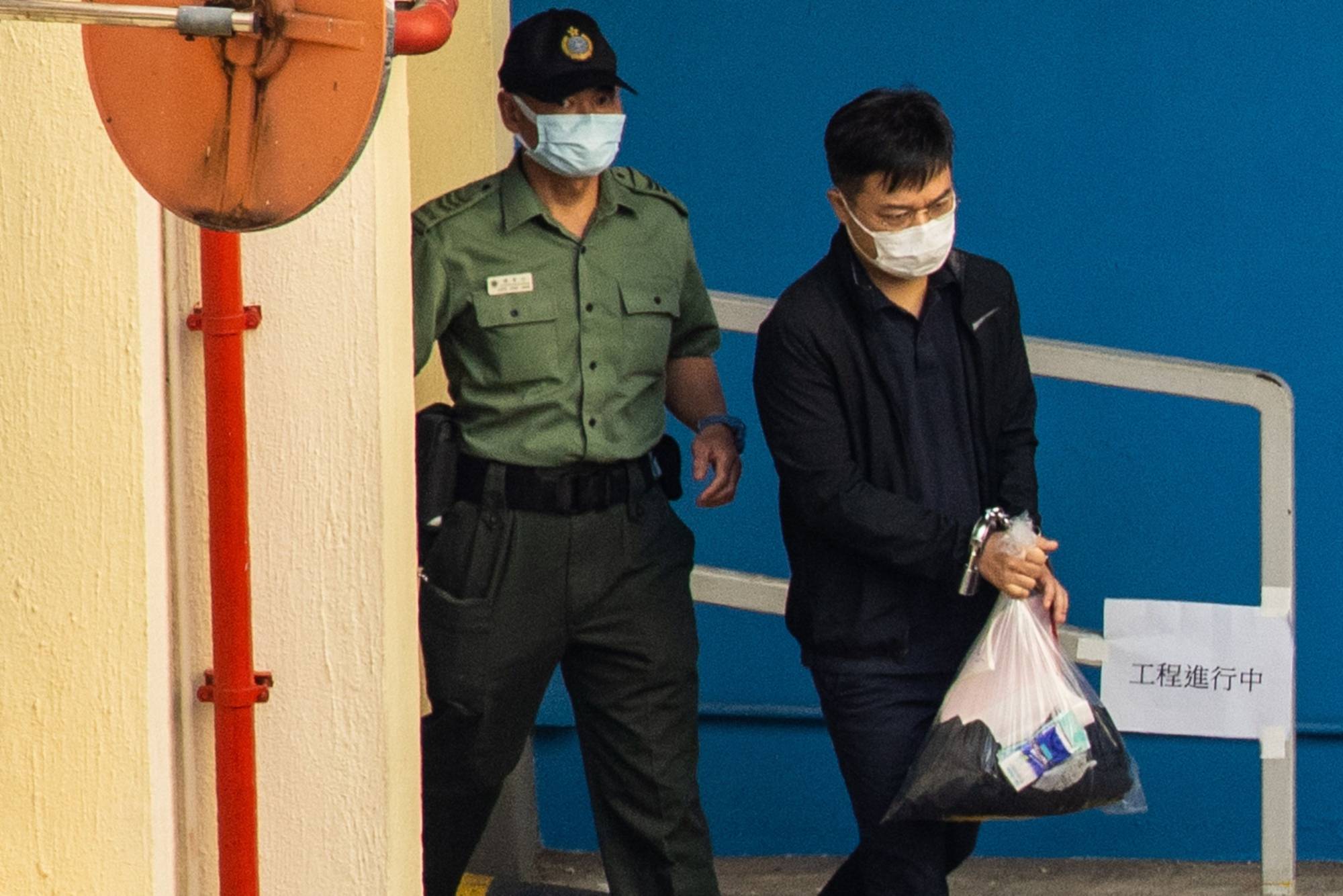Ryan Law, editor-in-chief of the now-defunct Apple Daily newspaper, is escorted to a Correctional Services Department vehicle at the Lai Chi Kok Reception Center to be transported to the West Kowloon Magistrates' Courts for a hearing in Hong Kong, China, on Friday, Aug. 13, 2021. | Bloomberg