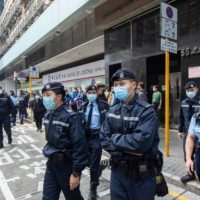 Police officers walk outside a building that houses the offices of online media outlet Stand News during a raid in Hong Kong, China, on Wednesday, Dec. 29, 2021. More 200 Hong Kong police raided pro-democracy media outlet Stand News and arrested six people connected to it, the latest actions likely to fuel concern about press freedoms in the city. | BLOOMBERG