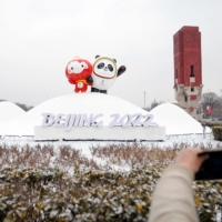 A pedestrian takes pictures of an installation featuring the mascots for the 2022 Winter Olympics and Paralympics in Beijing on Thursday. | REUTERS