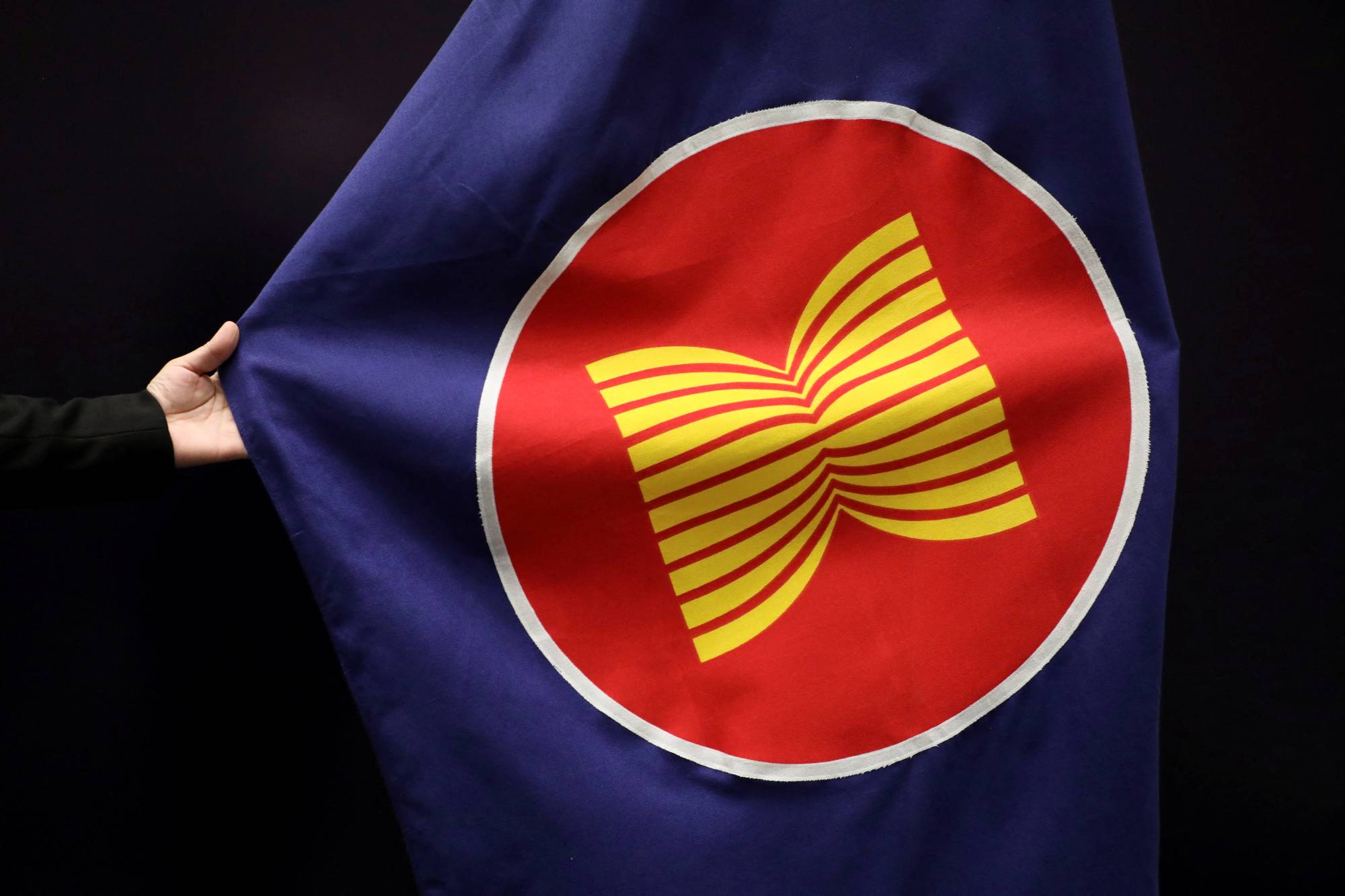 A worker adjusts an ASEAN flag at a meeting hall in Kuala Lumpur in October. | REUTERS