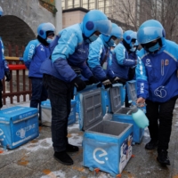 A driver of the Ele.me food delivery service disinfects the carrier trunks of his colleagues in Beijing on Thursday.  | REUTERS