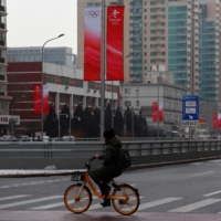 A man rides his bicycle outside the closed loop area designed to prevent the spread of the coronavirus near Olympic venues in Beijing on Thursday.  | REUTERS