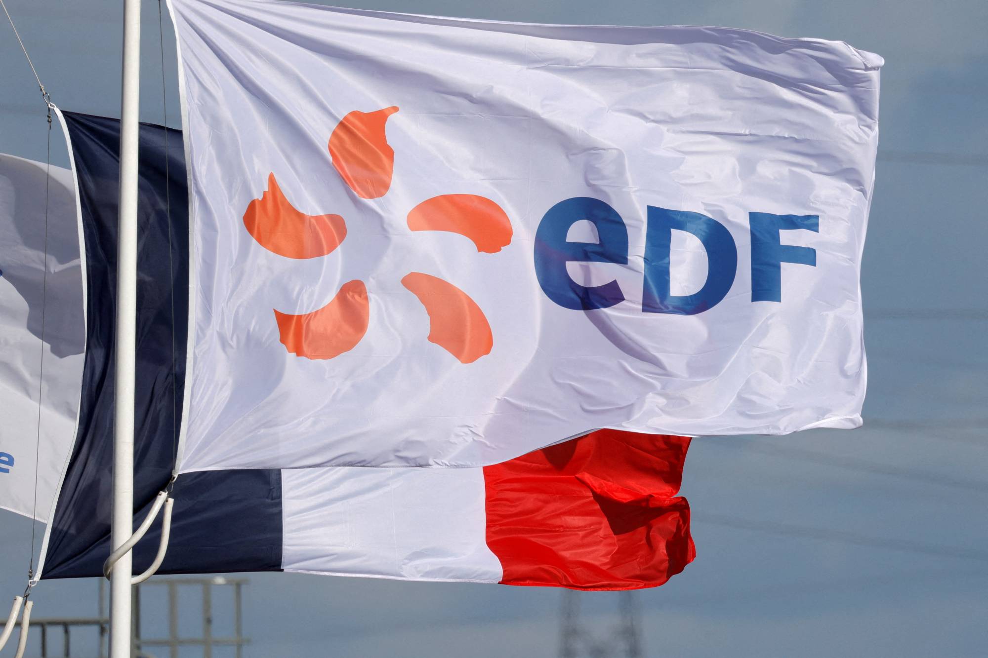 The logo of Electricite de France (EDF) flies next to the French flag fly near an EDF power plant in Bouchain, France, on Sep. 29. | REUTERS