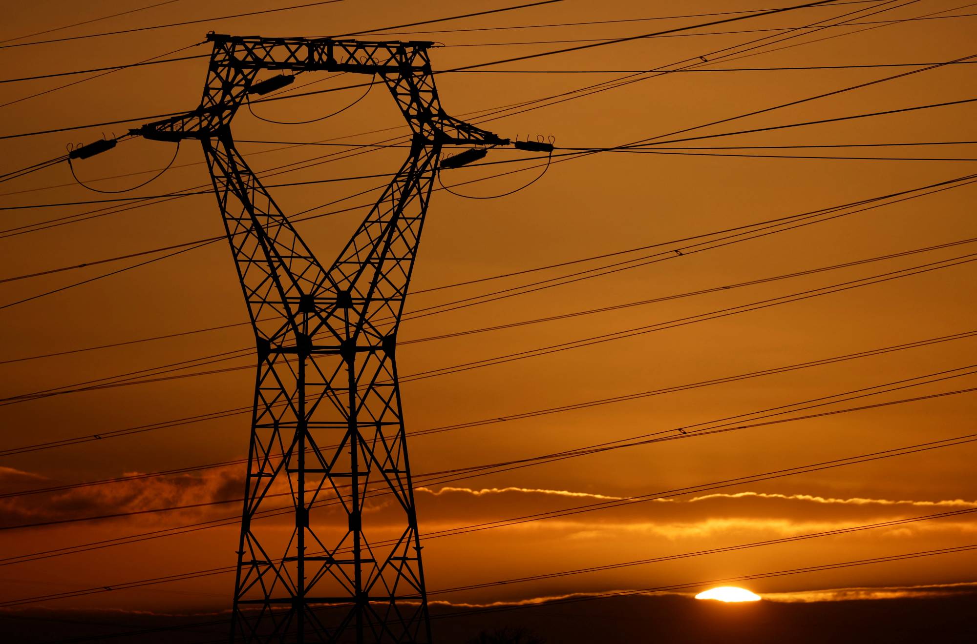 A pylon carrying high-tension electricity power lines stands against the sunset near Nantes, France, on Thursday. | REUTERS