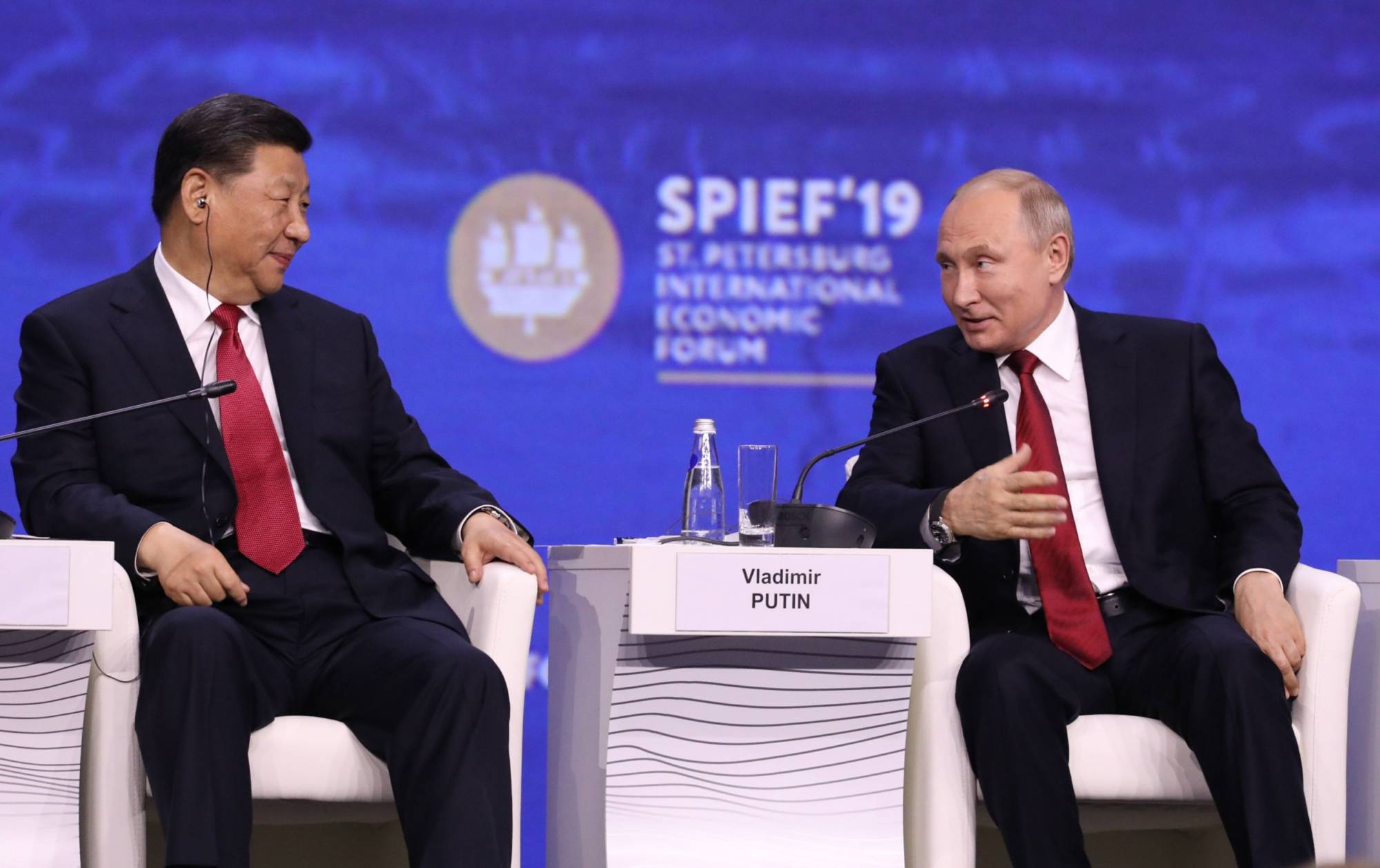 Russian President Vladimir Putin sits beside Chinese leader Xi Jinping during the St. Petersburg International Economic Forum in the Russian city in June 2019. | Bloomberg