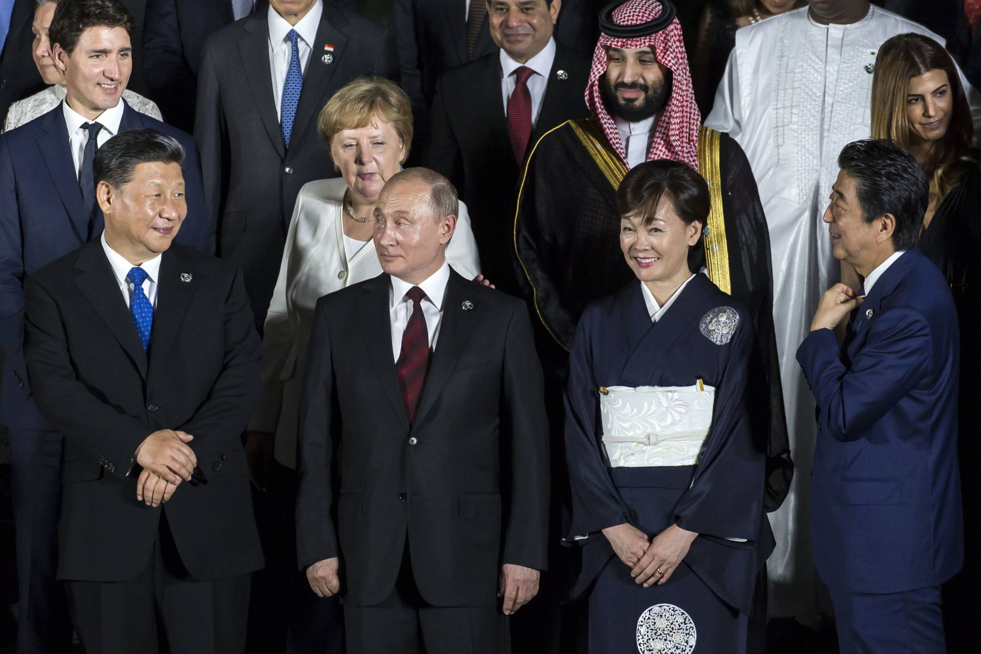 From left to right, Canadian Prime Minister Justin Trudeau, Chinese President Xi Jinping, former German Chancellor Angela Merkel, Russian President,Vladimir Putin, Saudi Arabia's Crown Prince Mohammed Bin Salman, Akie Abe, wife of Japan's former Prime Minister Shinzo Abe, and Shinzo Abe, along with other world leaders and delegates posing for a family photograph at the G20 summit in Osaka in June, 2019. | Bloomberg