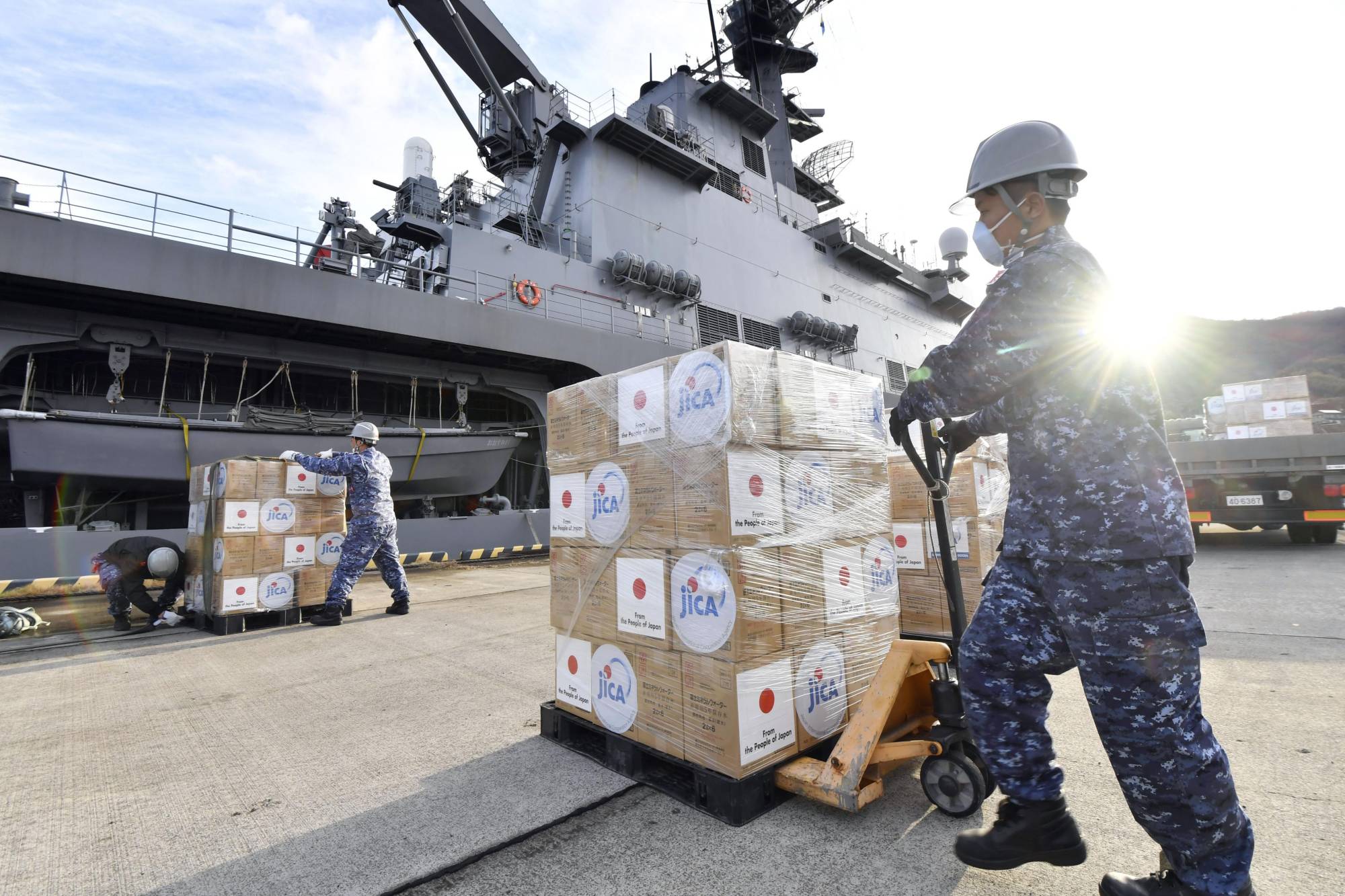 Self-Defense Force members load supplies onto a transport vessel docked at the Kure base in Hiroshima Prefecture Monday. The vessel departed for Tonga later in the day. | KYODO