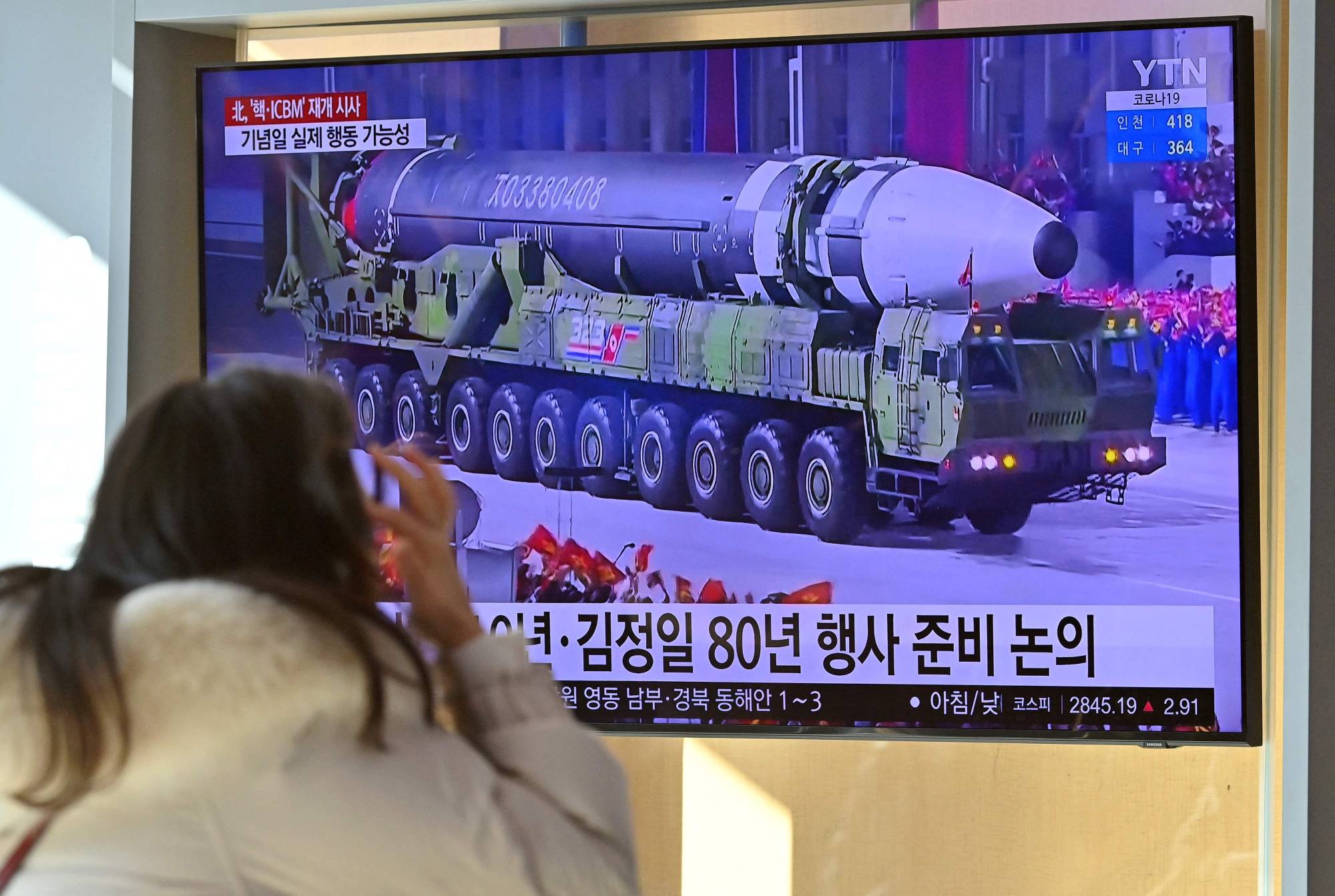 A woman watches footage of a North Korean missile following a string of sanction-busting missile launches this month. | AFP-JIJI