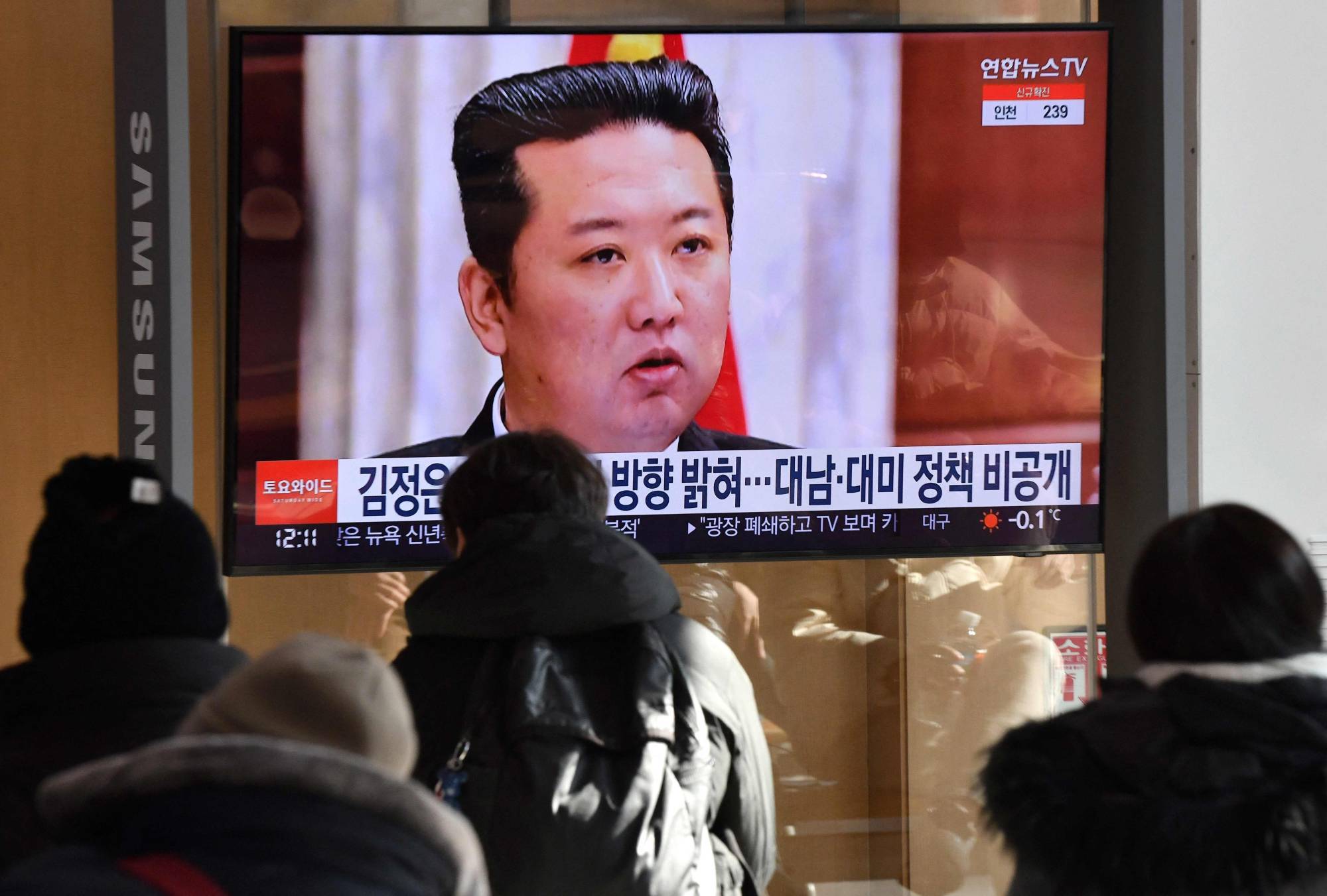 People watch a TV news program showing a picture of North Korean leader Kim Jong Un attending a meeting of the Central Committee of the Workers' Party of Korea, at the main railway station in Seoul on Jan. 1. | AFP-JIJI