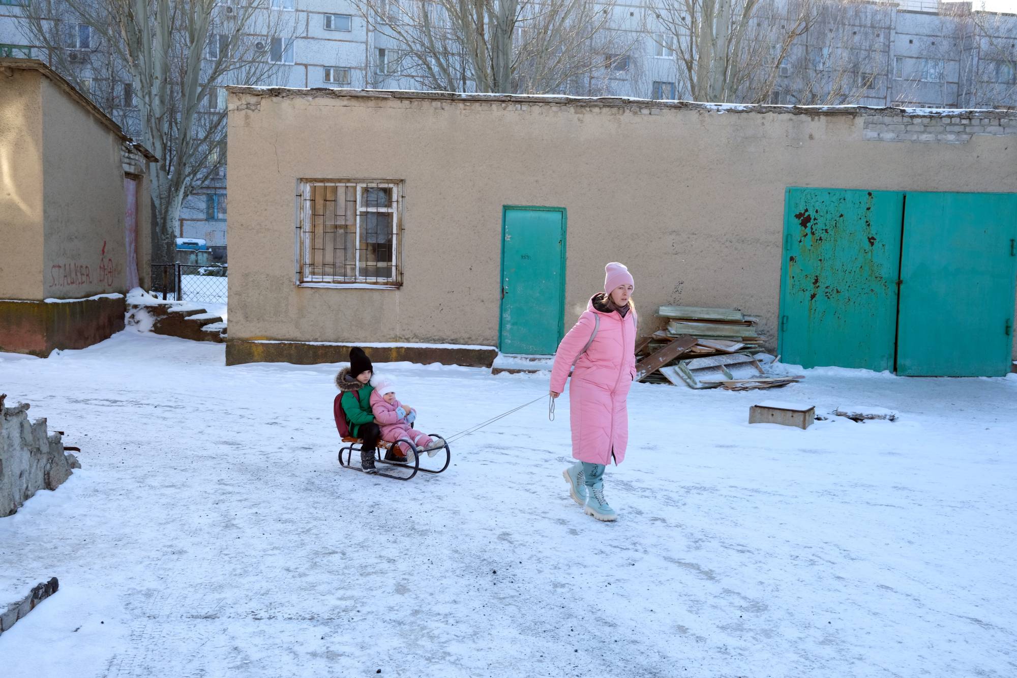 Children are pulled on a sled in Svitlodarsk, near the front lines in eastern Ukraine, on Saturday. | Tyler Hicks/The New York Times