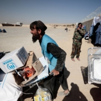 An UNHCR worker distributes supplies to displaced Afghans outside a distribution center near Kabul in late October. | REUTERS