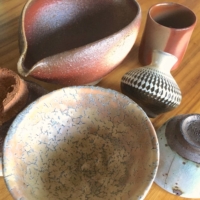 Pieces made with the crazing technique define Hagi and Kiyomizu ware in the front row, while in the back are a wood ash-glazed Bizen ware bowl, a straw-wrapped cup and a chattered piece of Onta ware. | SAMANTHA SEGHERS
