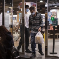 Members of the public exit a restaurant carrying bags of take-out food in the Causeway Bay area of Hong Kong on Friday, Jan. 7. | BLOOMBERG