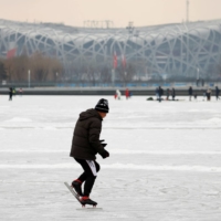 People skate on a frozen canal in front of Beijing\'s National Stadium, where the opening and closing ceremonies of the Winter Games will be held, on Jan. 20.  | REUTERS