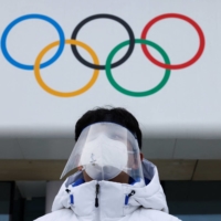 A volunteer wearing a face mask and shield is seen at the National Aquatics Center in Beijing on Sunday. | REUTERS