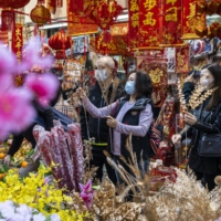Shoppers look at flowers and Lunar New Year decorations at a stall in Hong Kong on Sunday.  | BLOOMBERG
