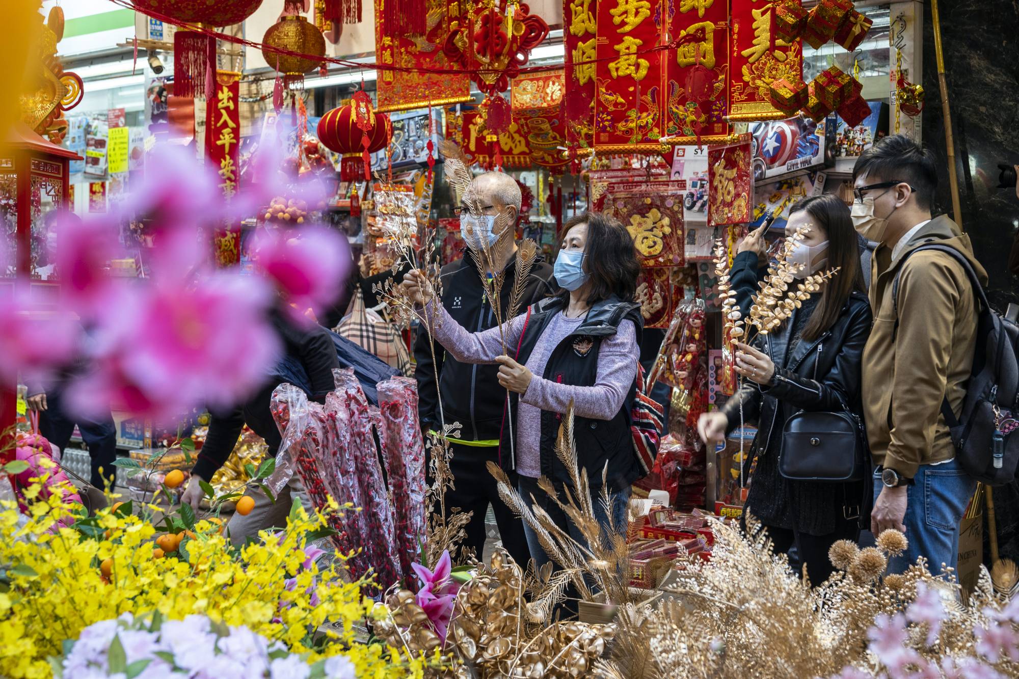 Shoppers look at flowers and Lunar New Year decorations at a stall in Hong Kong on Sunday. | Bloomberg