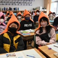 Students at Yamato Elementary School in Sendai wear protective hoods on Dec. 10. | KAHOKU SHIMPO
