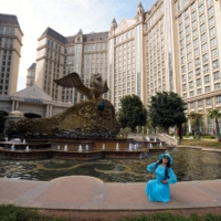 A visitor poses for pictures at Castle Hotel on the man-made Ocean Flower Island, a resort developed by China Evergrande Group, in Danzhou, Hainan province, China, on Jan. 7. | REUTERS