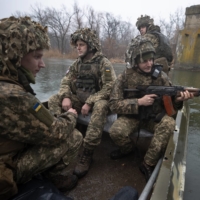 Ukrainian soldiers use a boat to cross a river to one of their front line positions in Schastia, Ukraine, on Feb. 3.  | TYLER HICKS / THE NEW YORK TIMES