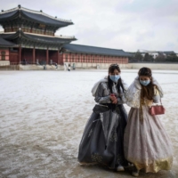 Visitors wear traditional hanbok dress as they walk on the grounds of the Gyeongbokgung Palace after a snowfall in Seoul on Jan. 17.  | AFP-JIJI