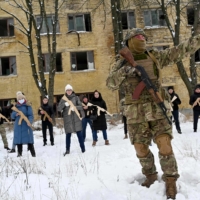 A military instructor teaches civilians holding wooden replicas of Kalashnikov rifles during a training session at an abandoned factory in Kyiv on Jan. 30.  | AFP-JIJI