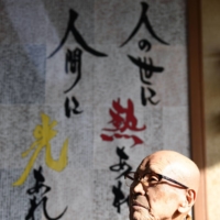 Hikari recalls his past experiences in front of calligraphy featuring a phrase from the Suiheisha Declaration, in Fukuoka Prefecture on Dec. 15. | NISHINIPPON SHIMBUN