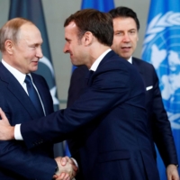 Russian President Vladimir Putin shakes hands with French President Emmanuel Macron during the Libya summit in Berlin on Jan. 19. | REUTERS