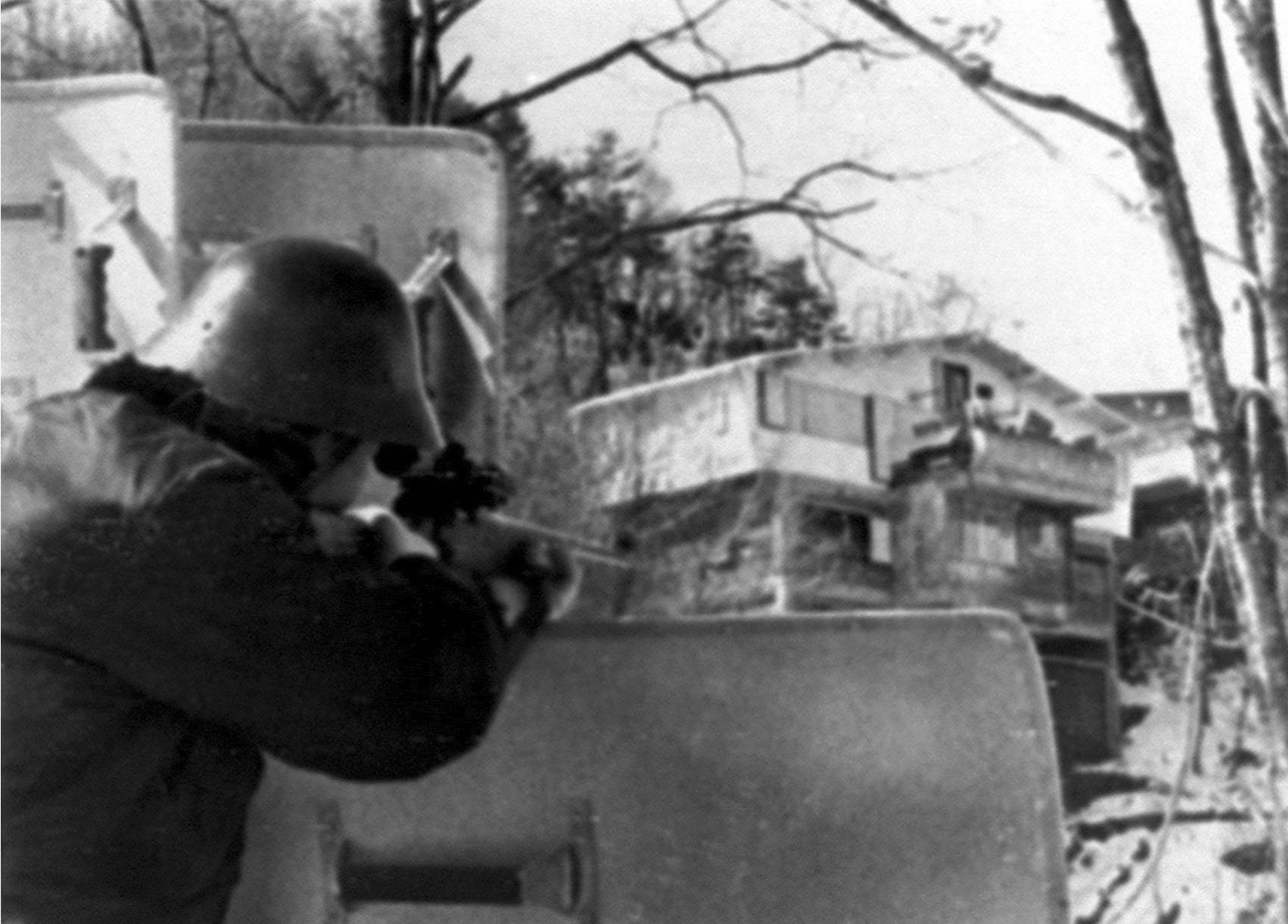 A police sniper aims a rifle at Asama-Sanso lodge in February 1972 in the town of Karuizawa, Nagano Prefecture. | KYODO