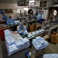 Workers inspect face masks at a factory on the outskirts of Ahmedabad, India, in February 2020. | REUTERS