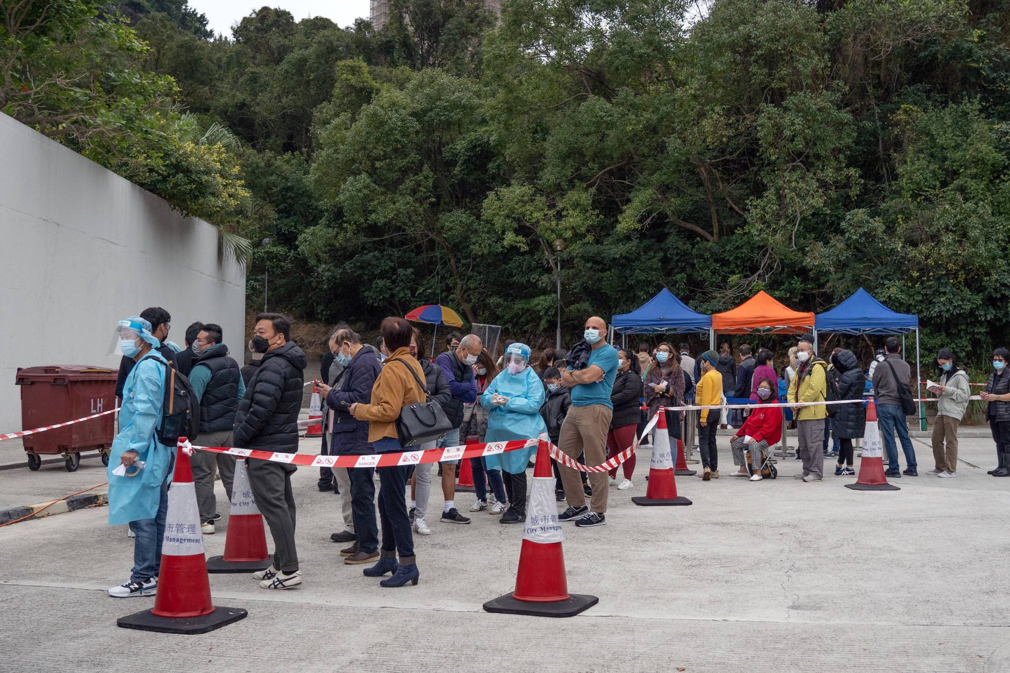 Residents wait in line at a COVID-19 testing facility in Hong Kong on Wednesday. | Bloomberg