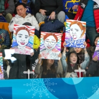 Fans hold drawings of the South Korean women\'s curling team during the 2018 Pyeongchang Olympics in South Korea. | CHANG W. LEE / THE NEW YORK TIMES