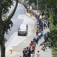 People queue at a mobile specimen collection station for COVID-19 testing in Hong Kong\'s Tung Chung district on Thursday as authorities scrambled to ramp up testing capacity following a record high number of new infections.  | AFP-JIJI